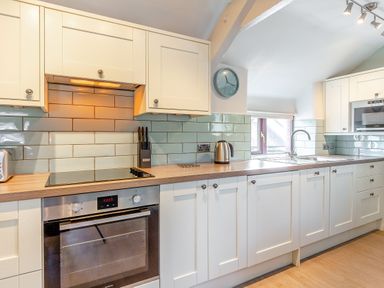 A kitchen with units, oven, and sink at Crabtree Cottage in Bude