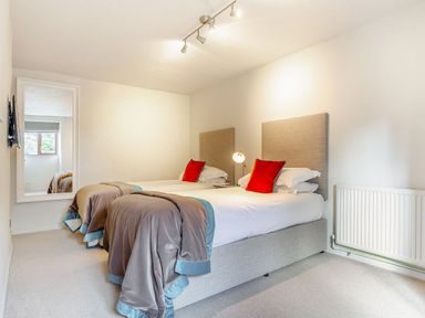 A bedroom with two beds and a mirror at Crabtree Cottage in Bude