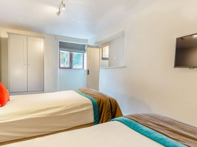 A bedroom with two beds and a wardrobe at Crabtree Cottage in Bude