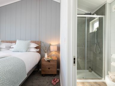 A bedroom with a shower visible through an adjacent door at Kynance Spa in Bude