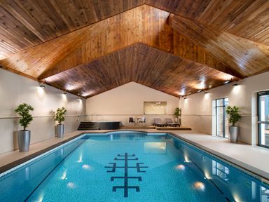 An indoor pool area with loungers and wooden ceiling at Kynance Spa in Bude