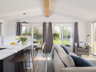 A living room with a sofa and a kitchen island at Mullion 2 Spa (Pet) in Bude