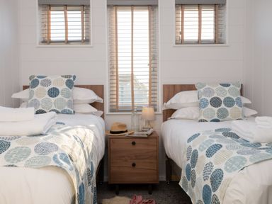 A bedroom with two beds and a bedside table at Mullion 2 Spa (Pet) Bude