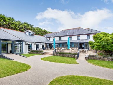 An outdoor area with a building, pathway, and patio at Mullion 2 Spa (Pet) Bude