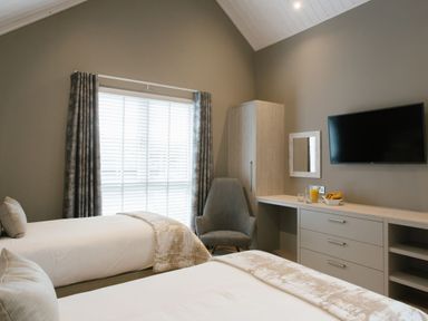 A bedroom with two beds and a television in The Glasshouse in Bude