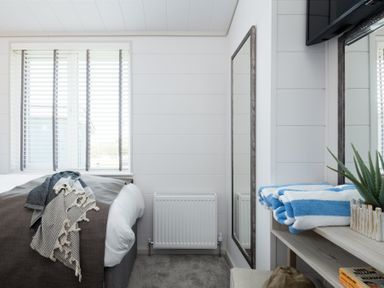 A bedroom with a bed and a mirror at Sennen 3 Spa Roof Terrace (Pet) Bude