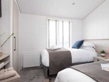 A bedroom with two beds and a window at Sennen 3 Spa Roof Terrace in Bude