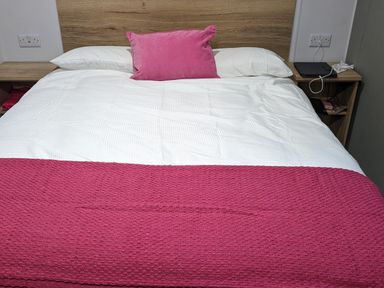 A bed with a pink throw and pillow at Willerby Ellerrton (delyn) Prestatyn