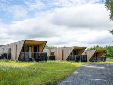 Three wooden cabins with balconies in a grassy area at Orka 2.0 Kinder (Pet) Dumfries