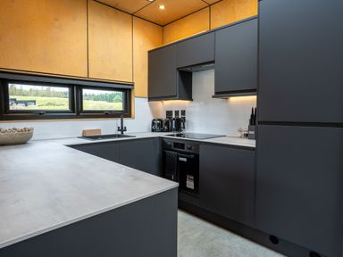 A kitchen with dark cabinets and a window at Orka Duo 2.0 (Pet) Dumfries