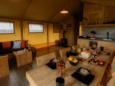A dining area with wooden furniture and kitchenette in Deluxe Safari Tent Fair Oak