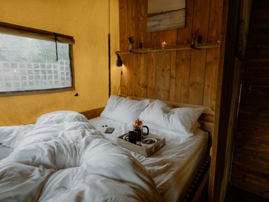 A bedroom with a bed and a basket on a nightstand at Deluxe Safari Tent in Fair Oak