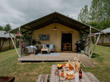 An outdoor area with a tent and seating at Deluxe Safari Tent in Fair Oak