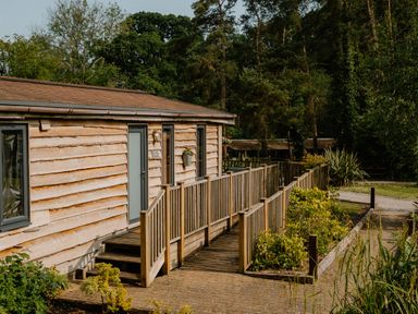 A cabin with a wooden deck and pathway at Spitfire Lodge in Fair Oak