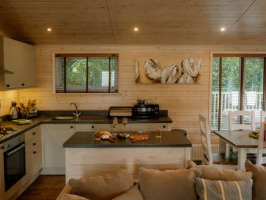 A kitchen with cabinets and a dining table at Spitfire Lodge in Fair Oak