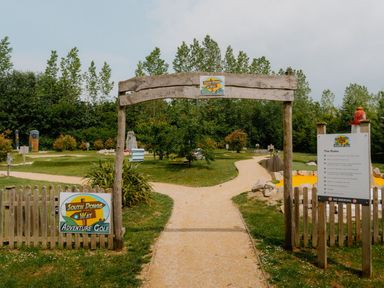 An entrance to an adventure golf area with a sign at South Downs Way Adventure Golf in Fair Oak