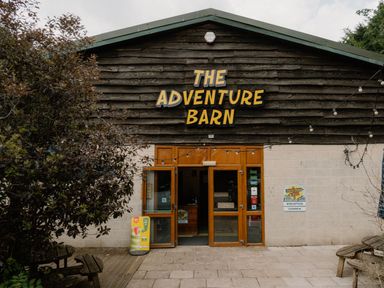 The entrance of The Adventure Barn with benches and plants at Spitfire Lodge Fair Oak