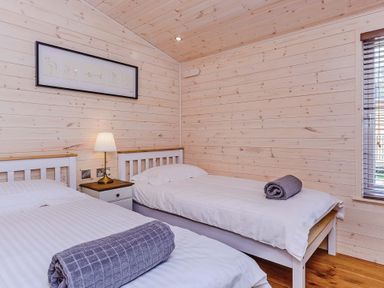 A bedroom with two beds and a bedside lamp at Lancaster Lodge in Fair Oak