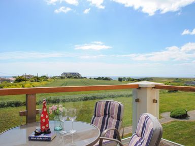 A terrace with a table and chairs overlooking a field at 8 Thurlestone Beach in Kingsbridge
