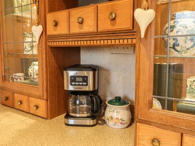 A kitchen with a coffee machine and a coffee canister at Llwyn Derw Talybont
