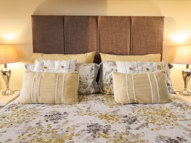 A bed with pillows and lamps in the bedroom at Llwyn Derw Talybont