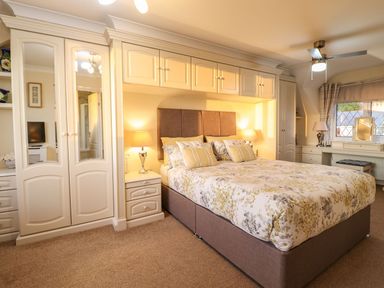 A bedroom with a bed and wardrobe at Llwyn Derw Talybont