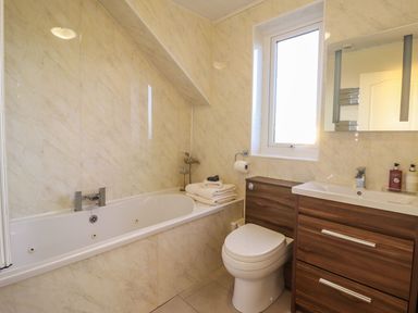 A bathroom with a bathtub, toilet, and sink at Llwyn Derw Talybont