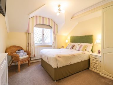 A bedroom with a bed and a chair at Llwyn Derw Talybont