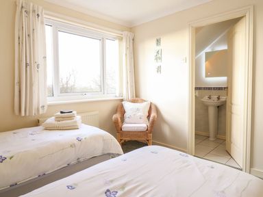 A bedroom with twin beds and a bathroom sink at Llwyn Derw in Talybont