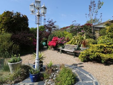 A garden with a lamp post and bench at Llwyn Derw in Talybont