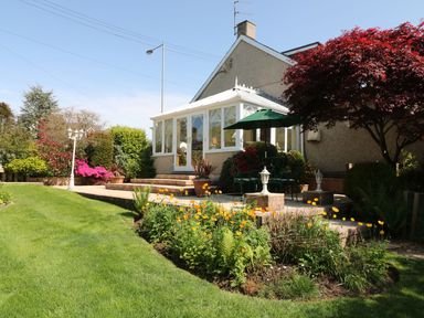 A garden with a porch and flower bed at Llwyn Derw in Talybont