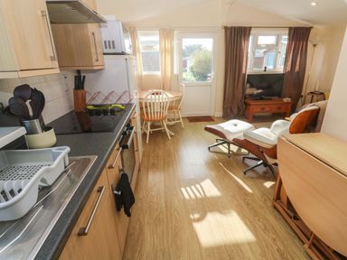 A kitchen with a dining area and television at Chalet 225 Tregolds near St Merryn
