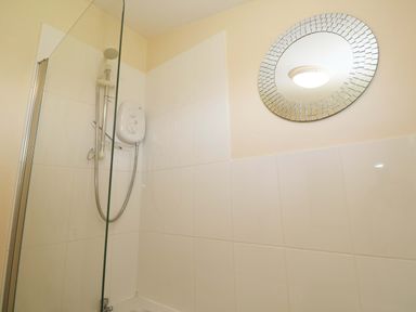 A shower area with a circular mirror at Chalet 225 Tregolds near St Merryn