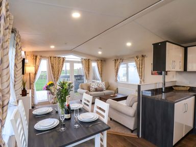A living room with a dining area and kitchen cabinet at Rosefinch Cabin in Scarborough