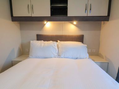 A bedroom with a bed and wall cabinets at Rosefinch Cabin in Scarborough