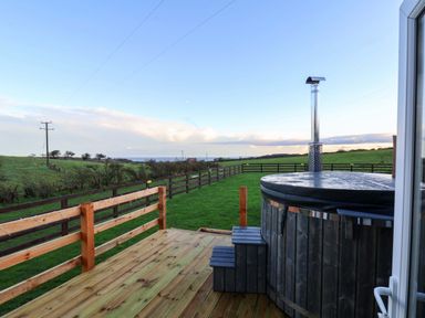 An outdoor area with a hot tub and wooden deck at Rosefinch Cabin in Scarborough