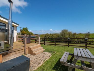 An outdoor seating area with a bench and gravel at Rosefinch Cabin Staintondale near Scarborough