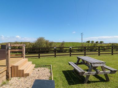 An outdoor area with a picnic table and a fence at Rosefinch Cabin in Staintondale near Scarborough