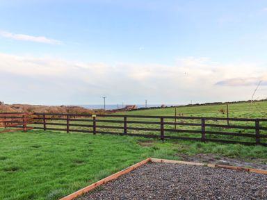 A garden with grass and a fenced area at Swift Cabin in Scarborough