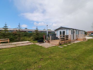 A cabin with a deck and hot tub at Swift Cabin Staintondale near Scarborough