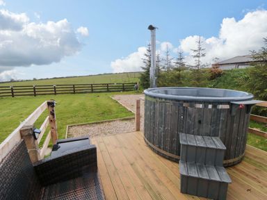 An outdoor area with a hot tub and seating at Swift Cabin in Staintondale near Scarborough