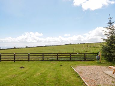 A grassy area with a fence and trees at Swift Cabin in Staintondale near Scarborough