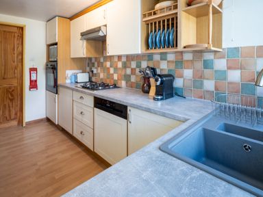 A kitchen with cabinets, sink, stove, and appliances at Oaks Lodge Cottage in Ambleside