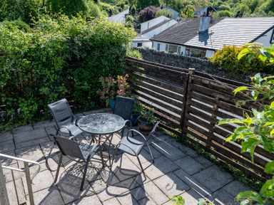 A garden with a table and chairs at Oaks Lodge Cottage in Ambleside