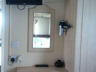 A bedroom with a mirror and hair dryer at Coopers Beach Holiday Park - Holiday Accommodation 3999 Mersea Island