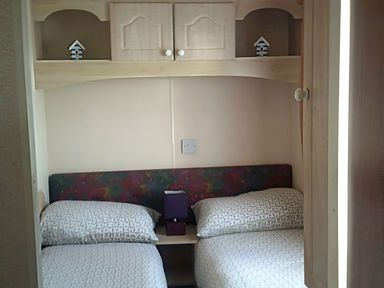 A bedroom with two beds and a shelf at Coopers Beach Holiday Park - Holiday Accommodation 3999, Mersea Island