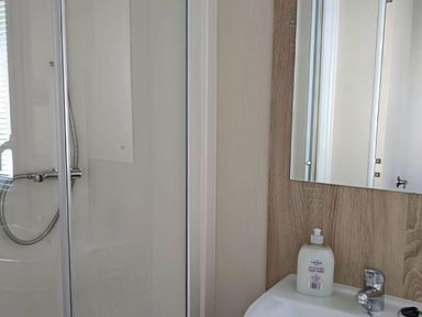 A bathroom featuring a shower, mirror, and sink at Coopers Beach Holiday Park - Holiday Accommodation 6404, Mersea Island
