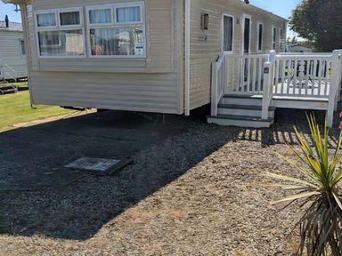 An outdoor area with a static caravan and deck at Coopers Beach Holiday Park - Holiday Accommodation 6404 Mersea Island