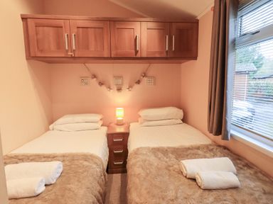 A bedroom with twin beds and a lamp at Kingfisher Lodge Grasmere 33, White Cross Bay near Windermere