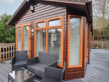A log cabin with outdoor furniture and glass table at Kingfisher Lodge, Grasmere 33, White Cross Bay near Windermere